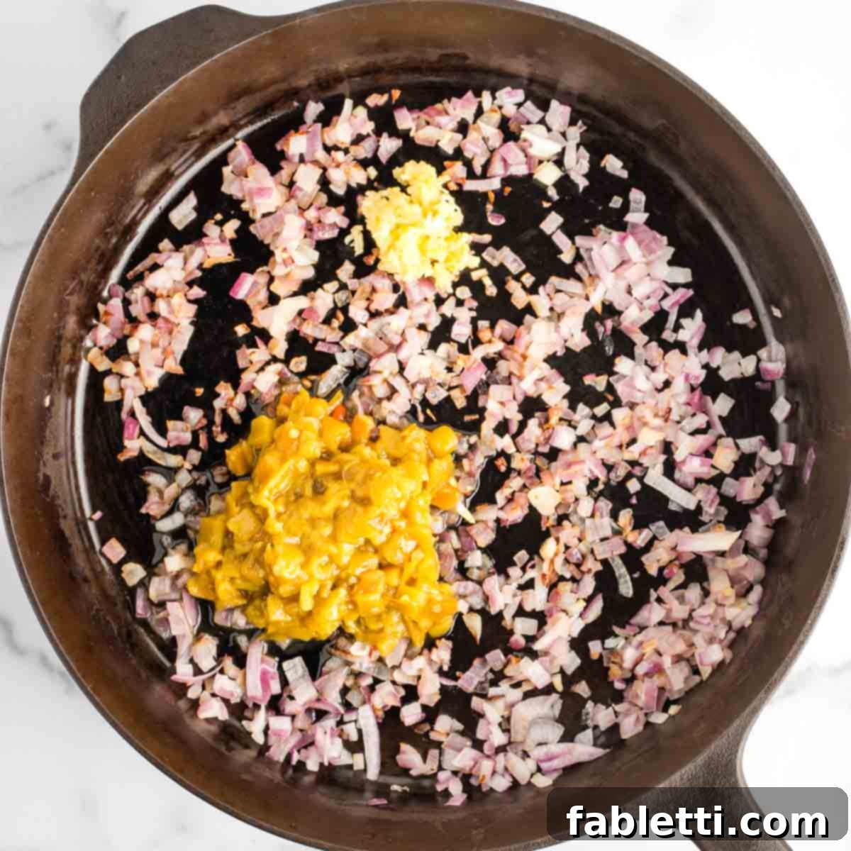 Effortless Skillet Plant-Based BBQ Beans 9 Sautéed diced red onions form the base in a cast iron skillet, now joined by fragrant minced garlic and a generous amount of diced green chiles, including their flavorful liquid.