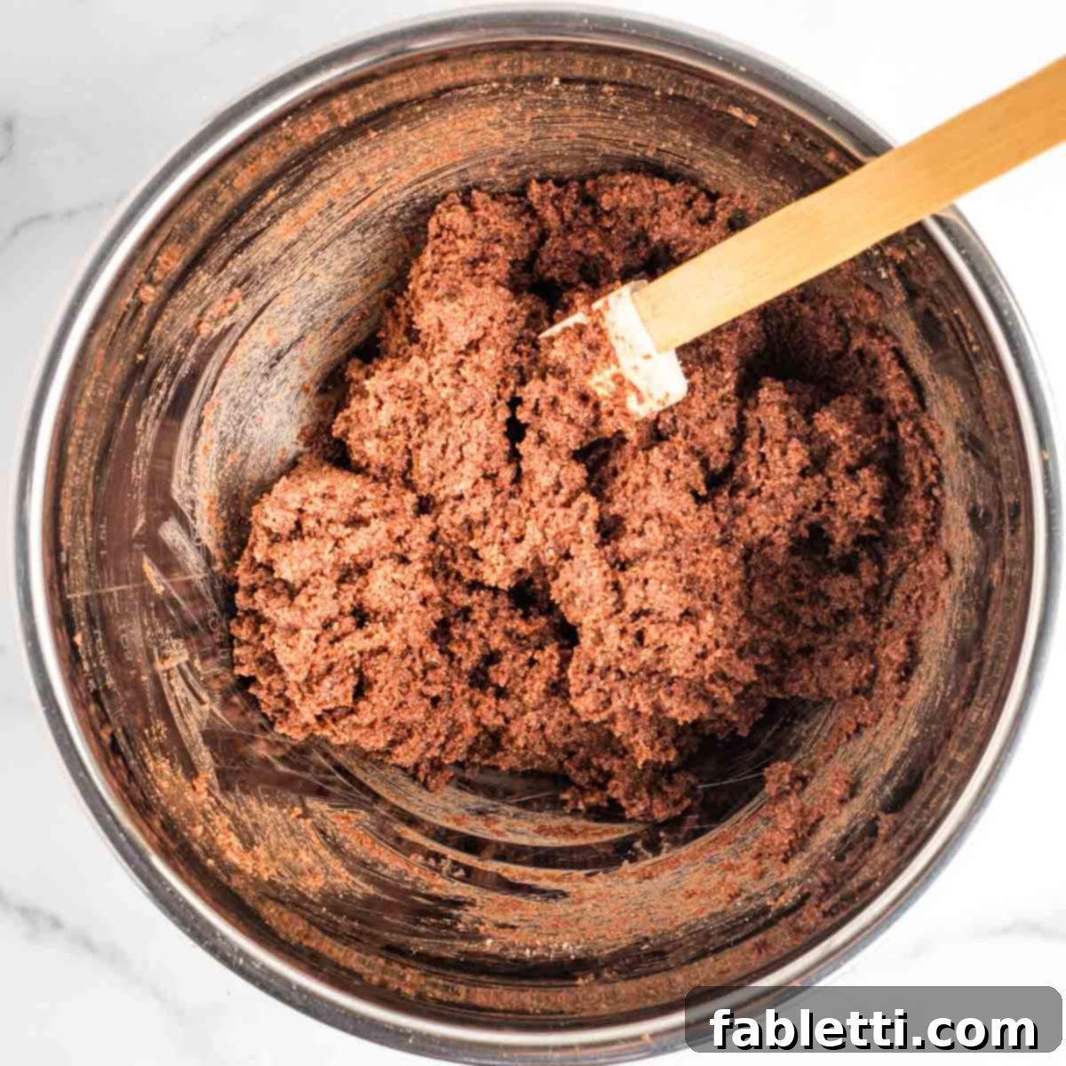 Irresistible Vegan Gluten-Free Chocolate Almond Biscotti 7 Spatula mixing chocolate biscotti batter in a silver bowl.