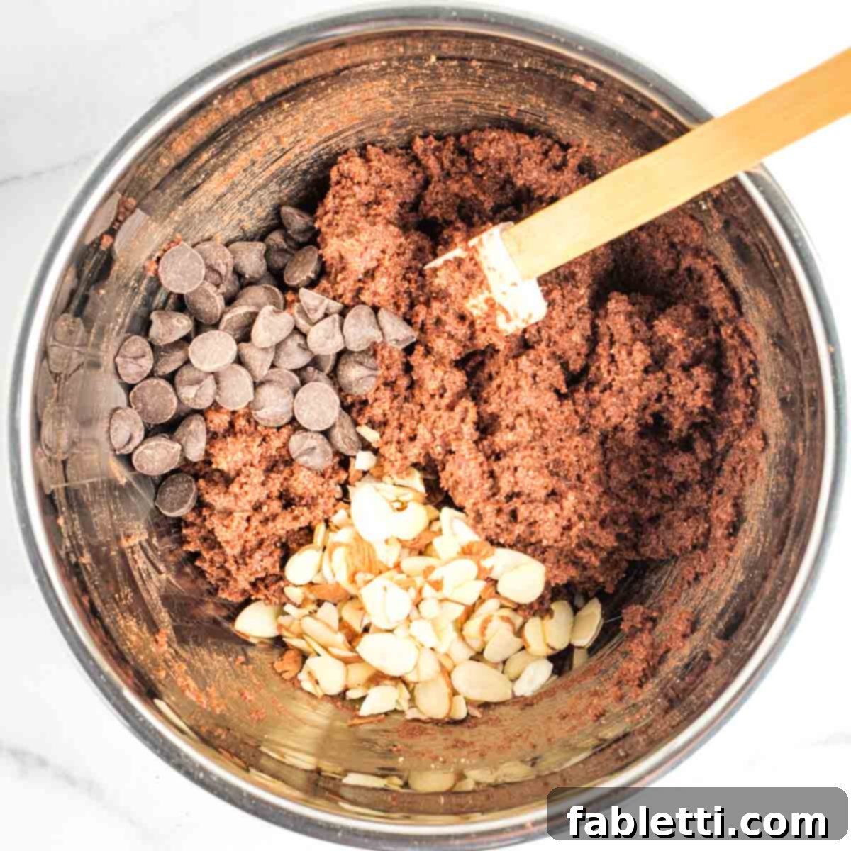 Irresistible Vegan Gluten-Free Chocolate Almond Biscotti 8 Chocolate biscotti batter, with a pile of chocolate chips and sliced almonds waiting to be mixed in.