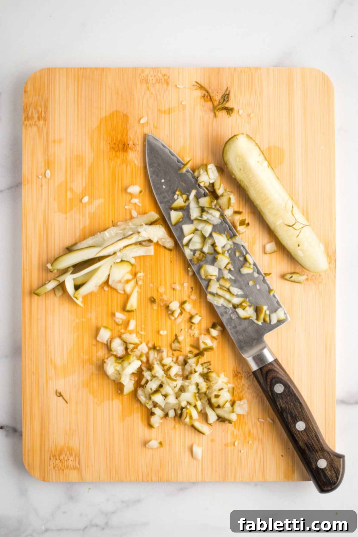 Creamy Tofu Vegan Big Mac Sauce 6 Cutting pickle spears into strips and then small diced cubes, on a wooden board.