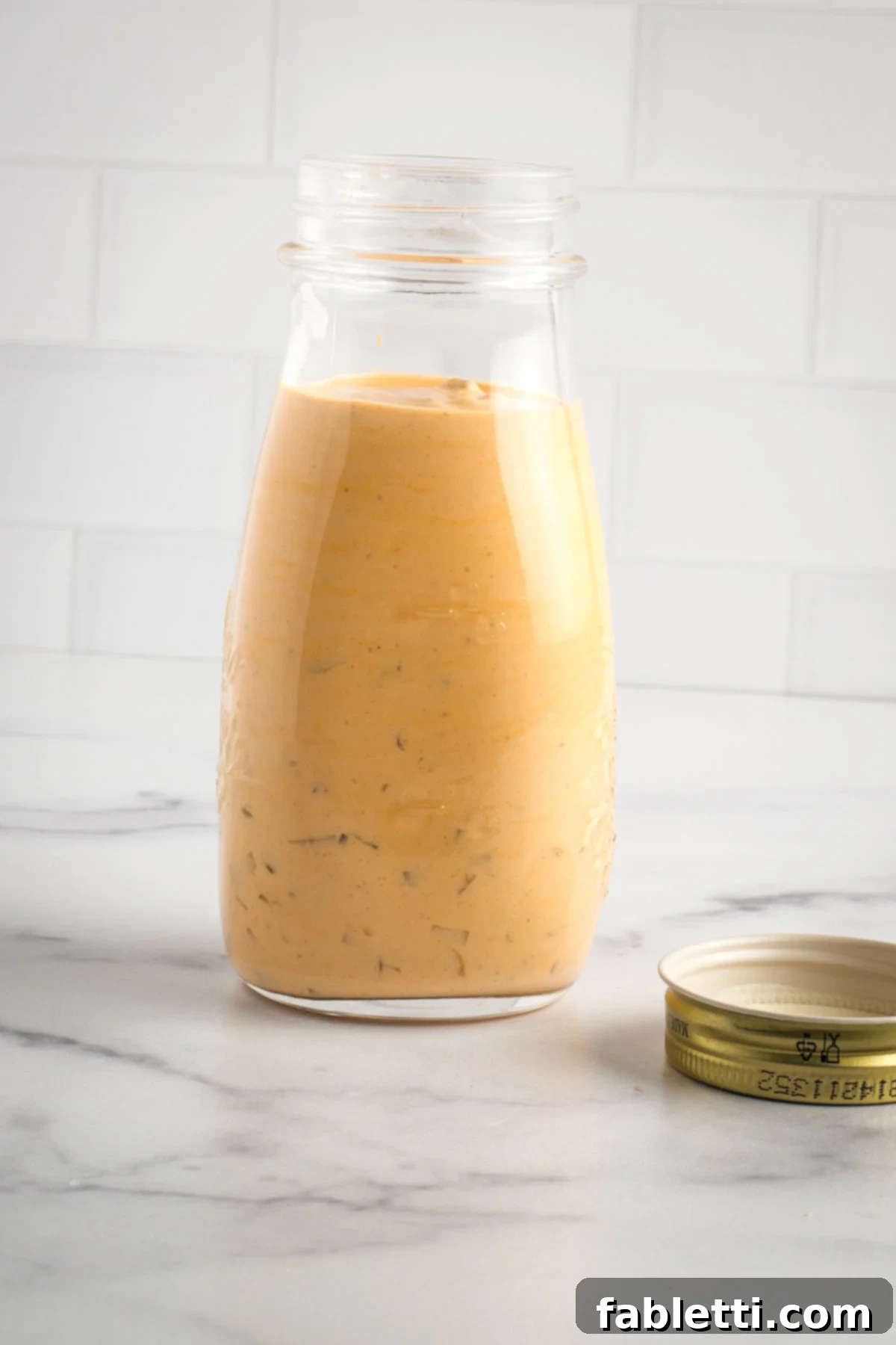 Creamy Tofu Vegan Big Mac Sauce 10 Small jar of burger sauce with diced pickles floating around.