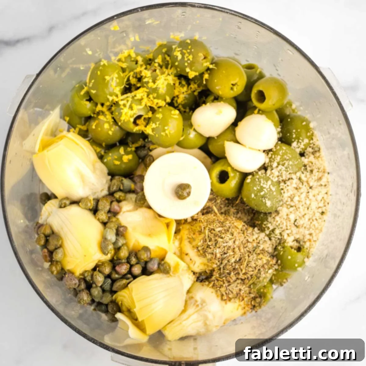 Olives, artichoke hearts, garlic, spices, hemp seeds. lemon zest in the bowl of a food processor. 