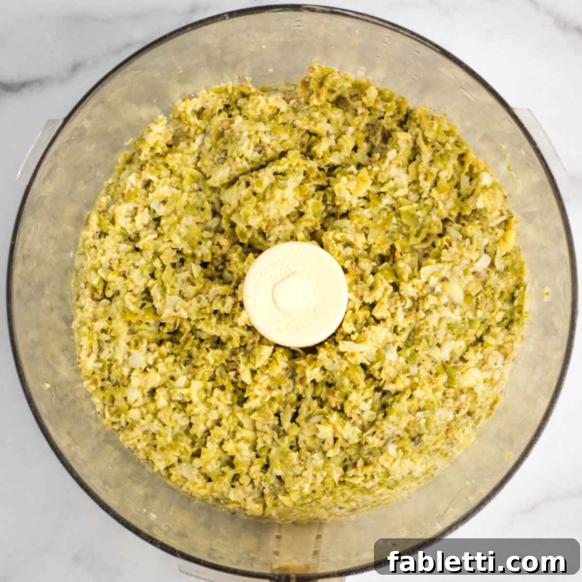 Chunky olive tapenade in the bowl of a food processor. 