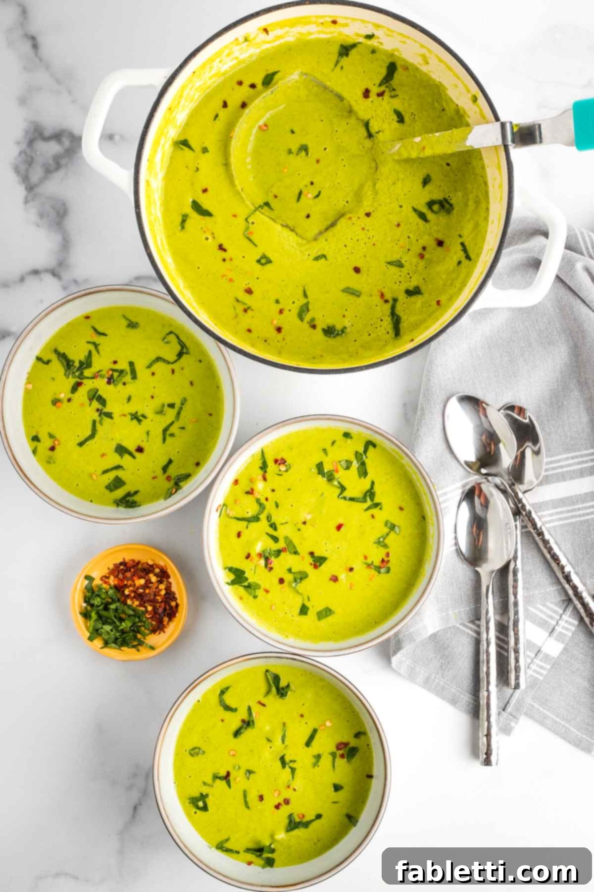 Sheet Pan Green Velvet Soup 2 Bowls of bright greenish yellow soup with fresh herbs and crushed red pepper on top plus a pot of same.