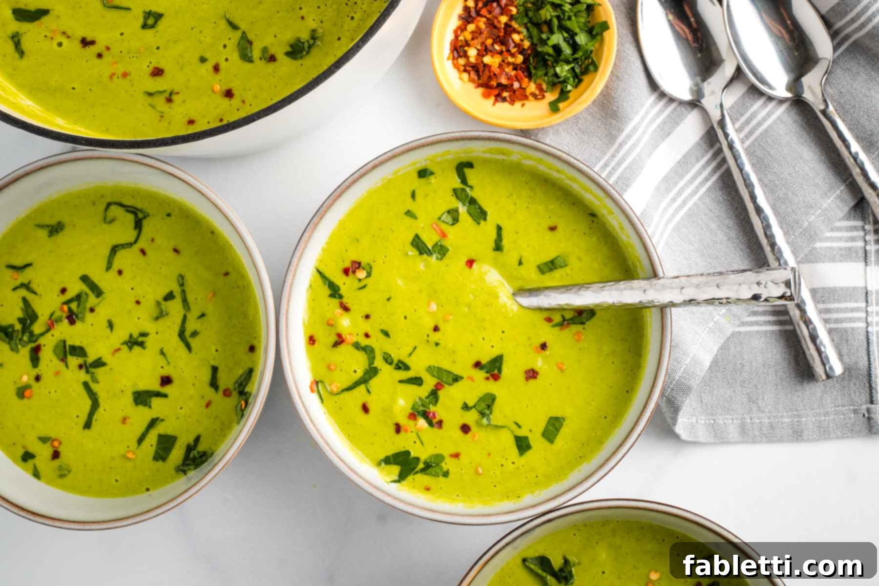 Sheet Pan Green Velvet Soup 14 Bowls of creamy pureed vegetable soup, garnished with fresh herbs and crushed red pepper.