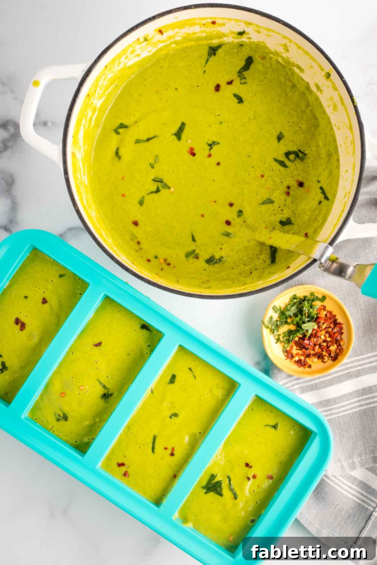 Sheet Pan Green Velvet Soup 15 Pot of green pureed vegetable soup and a ladle, transferring soup to souper cubes for freezing.