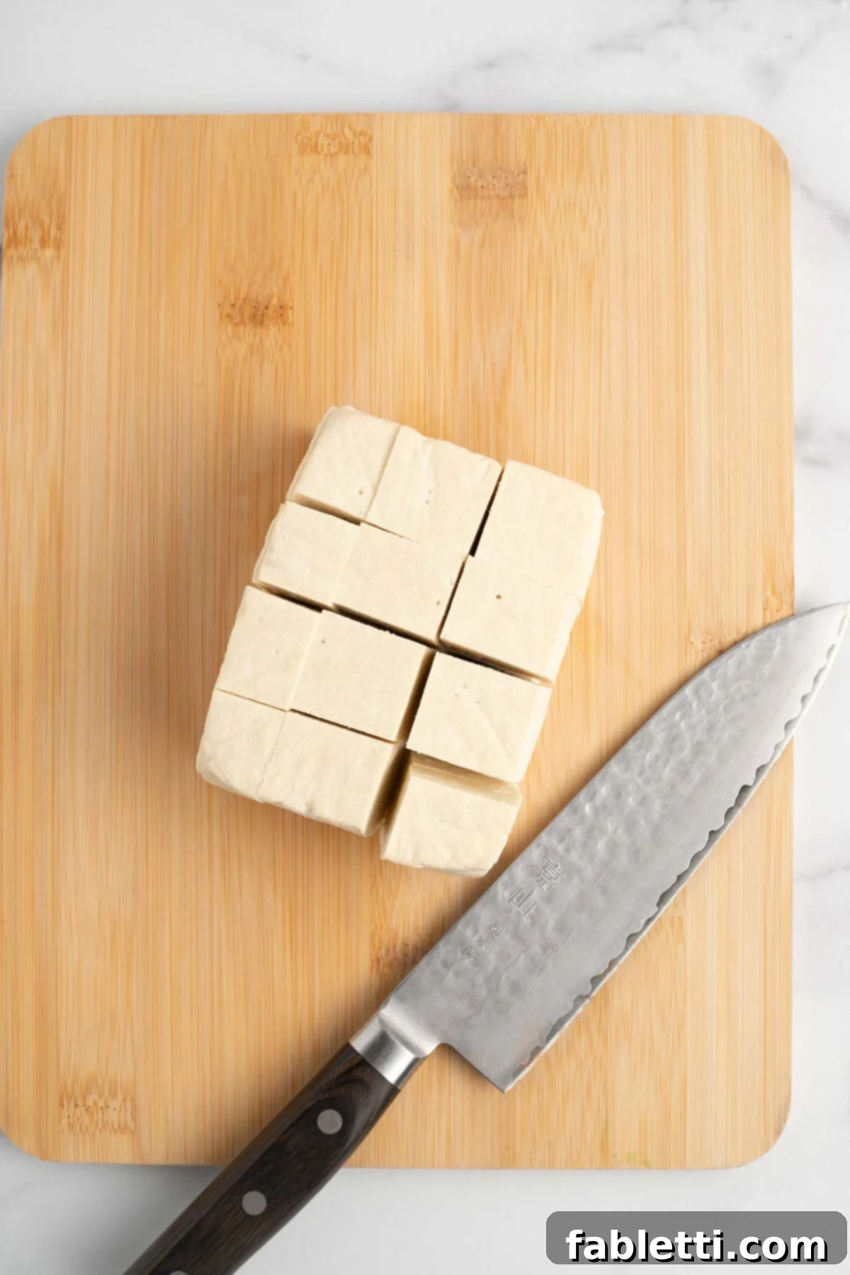 Stacked tofu slices cut into strips and then cubes.