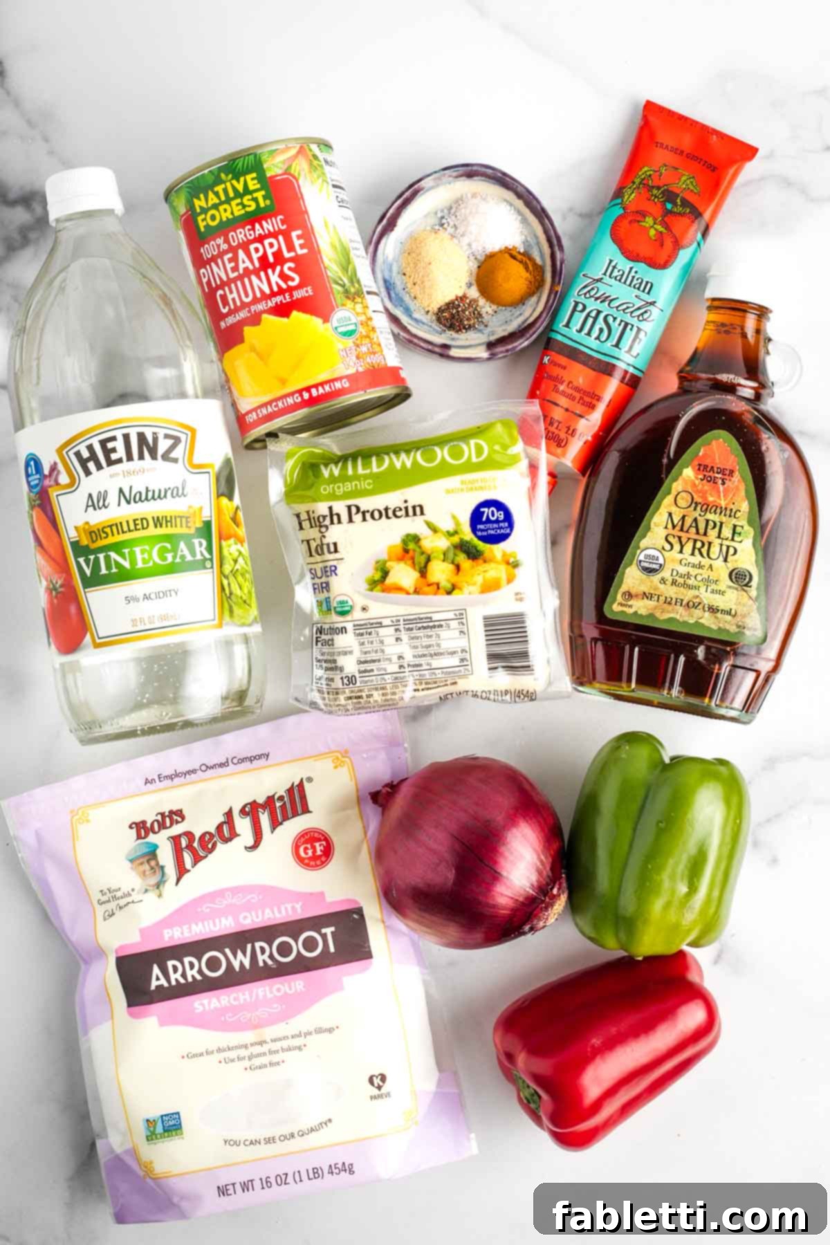 Ingredients for sweet and sour tofu: arrowroot powder, onion, bell pepper, tomato paste, maple syrup, vinegar, spices, canned pineapple, extra firm tofu.