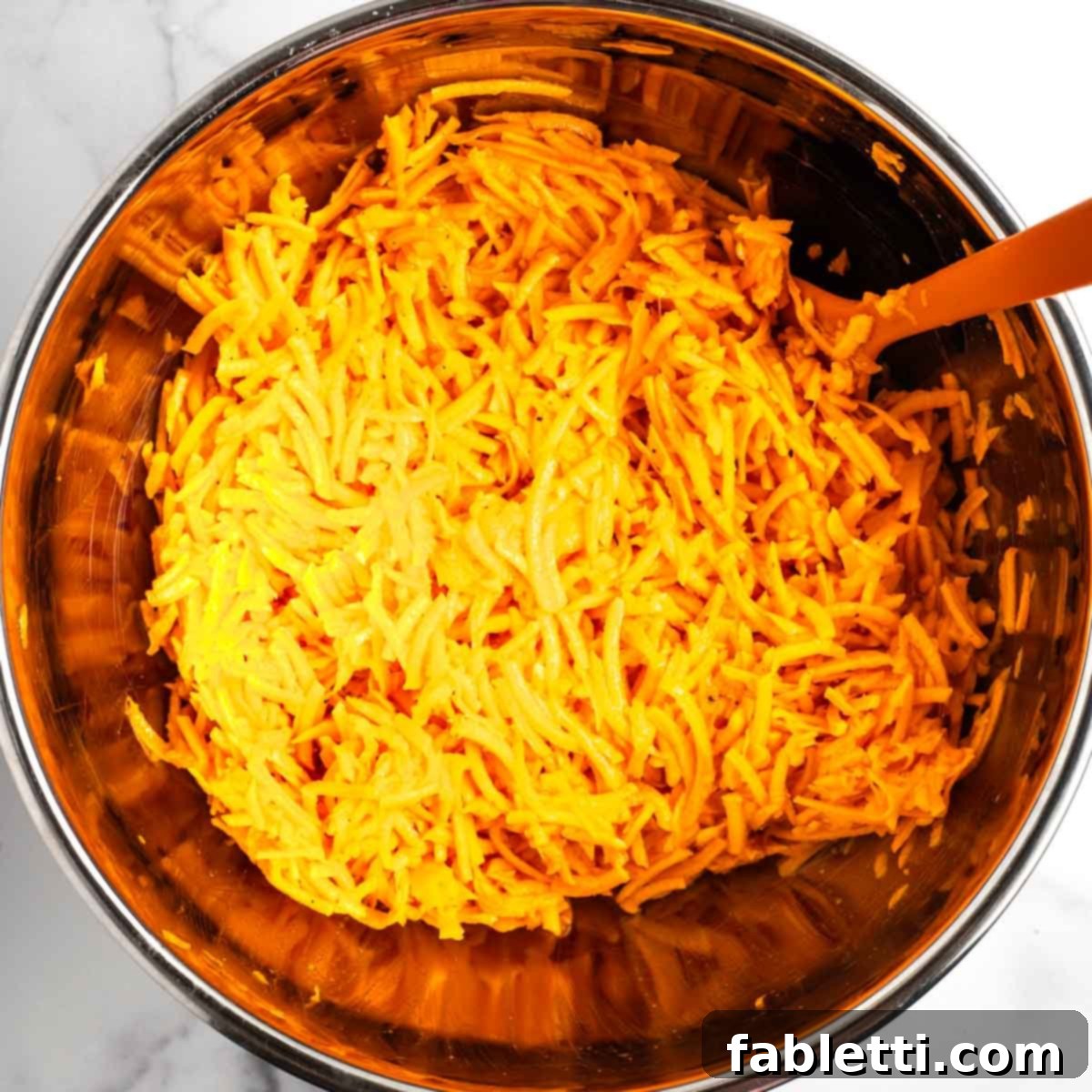 Golden Sweet Potato Kugel Cups 5 Shredded sweet potatoes in a bowl on top of whisked eggs.