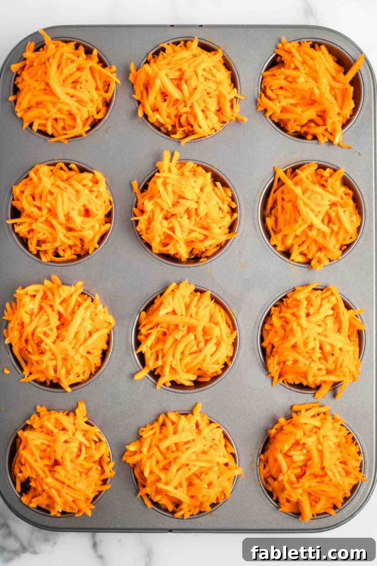 Golden Sweet Potato Kugel Cups 6 Muffin tins filled with shredded sweet potato and egg mixture.