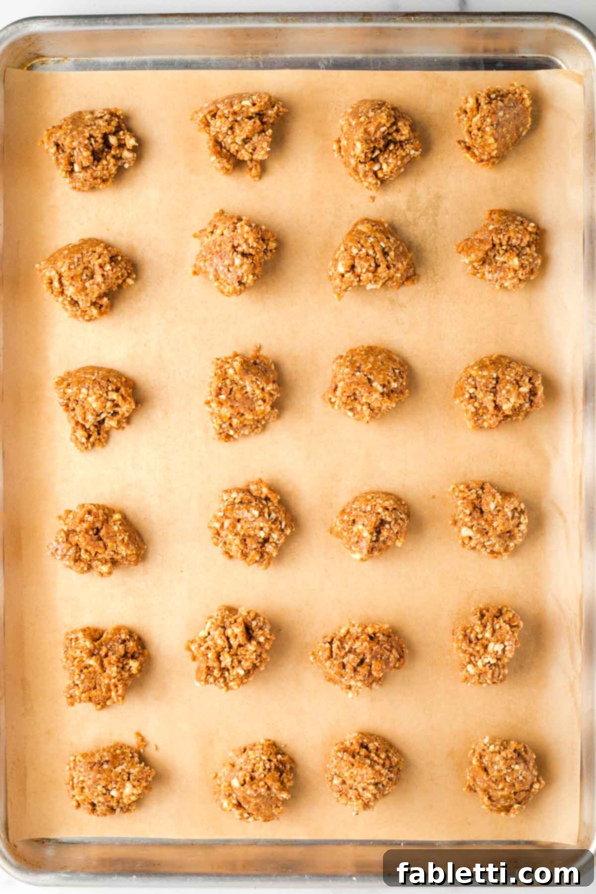 Decadent Vegan Chocolate Almond Macarons 11 Two dozen almond cookies dropped onto a parchment-lined baking tray.