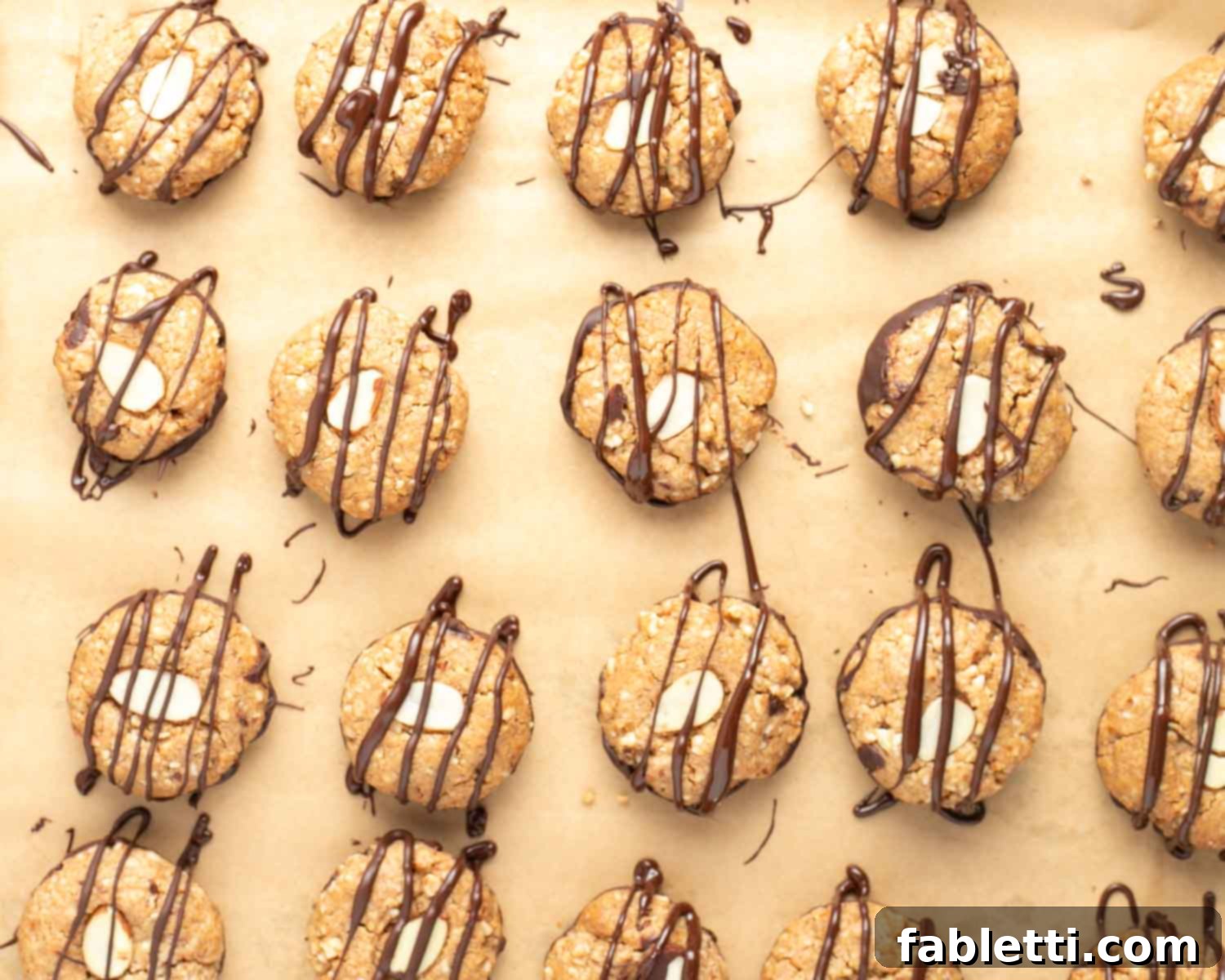 Decadent Vegan Chocolate Almond Macarons 19 Almond macaroons flipped right side up, resting on their hardened chocolate bases, with chocolate being drizzled over the tops.