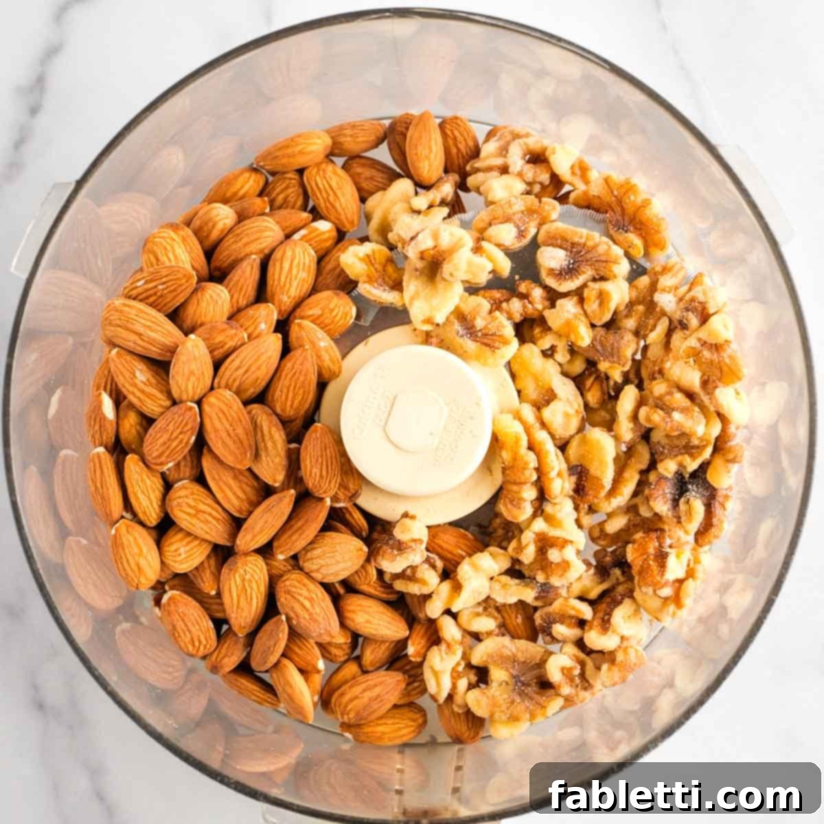 Decadent Vegan Chocolate Almond Macarons 6 Food processor bowl filled with whole almonds and whole walnuts.