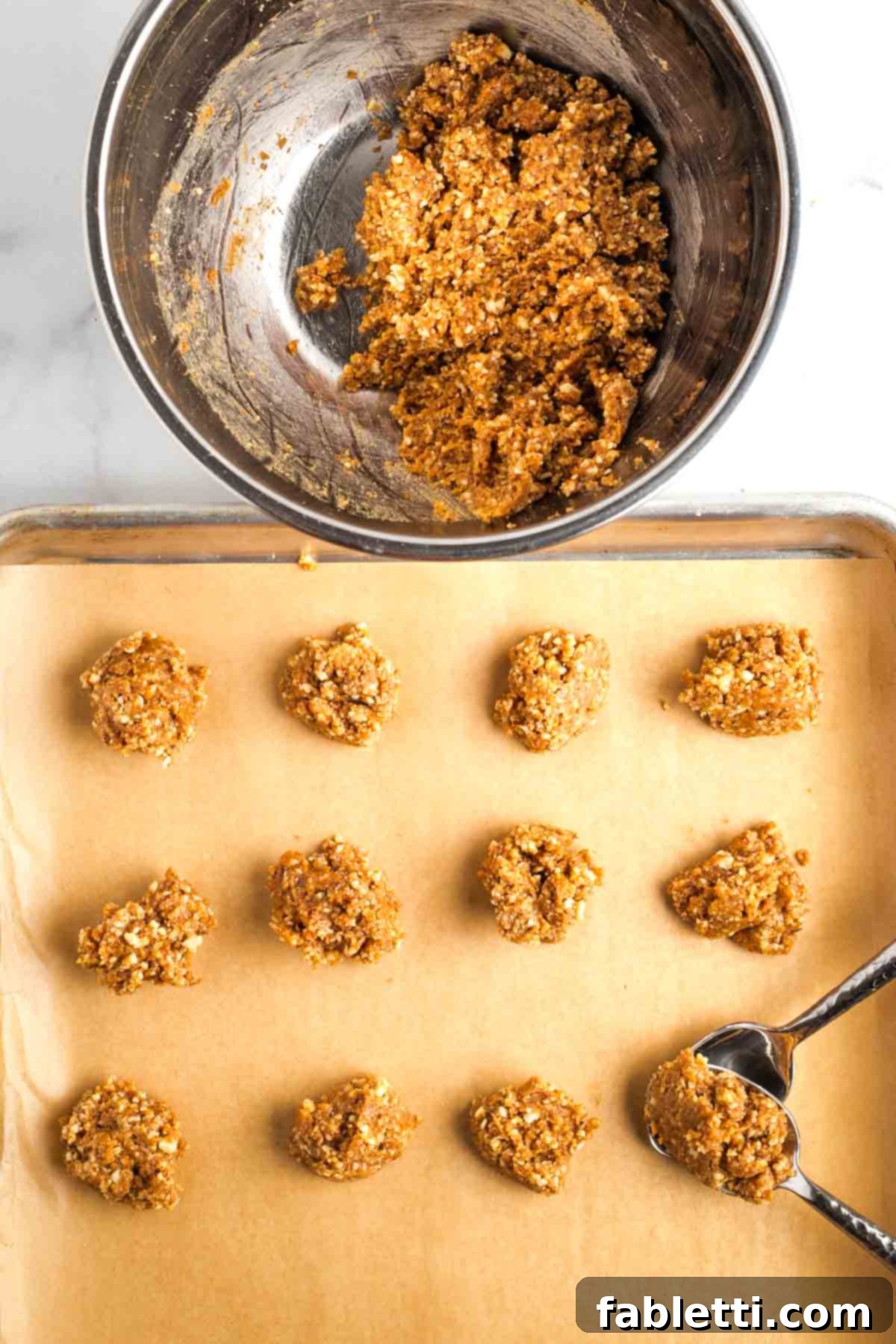 Decadent Vegan Chocolate Almond Macarons 10 Using two spoons to scoop cookie dough from the bowl onto a parchment-lined, rimmed baking sheet.