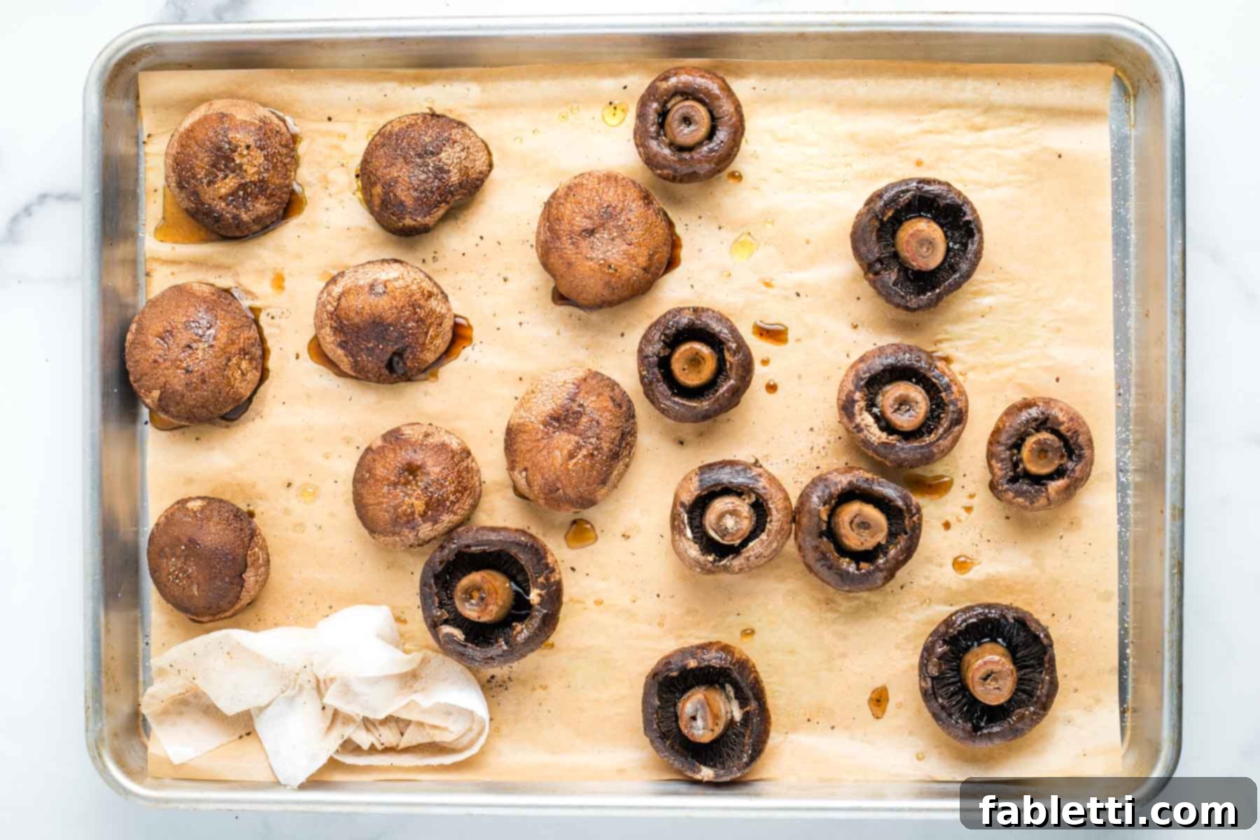 Zesty Chimichurri Portobello Steaks 7 Roasted mushrooms on a tray, cooked, half turned onto stems, half showing stems with a paper towel, absorbing the liquid.