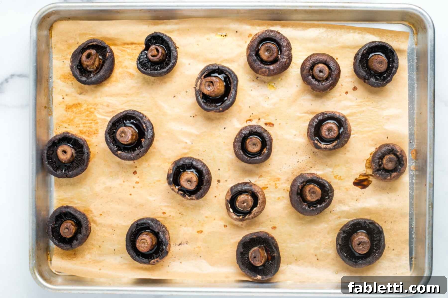 Zesty Chimichurri Portobello Steaks 8 Portobello mushrooms on a baking tray, stem side up, filled with mushroom liquid.