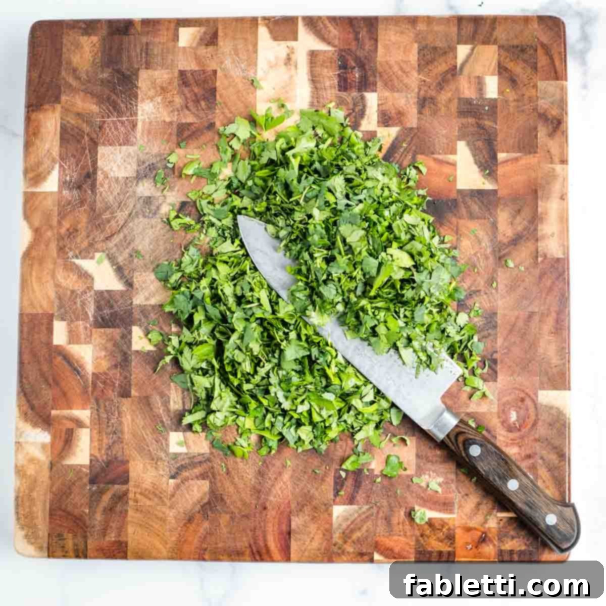Zesty Chimichurri Portobello Steaks 9 Chef's knife finely chopping a pile of fresh herbs.