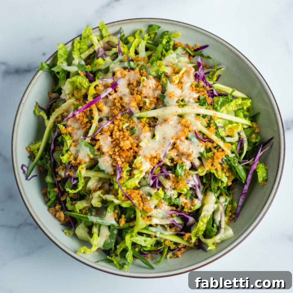 A simple, refreshing salad featuring crisp lettuce, cool cucumber, and shredded cabbage, generously sprinkled with savory crispy quinoa.