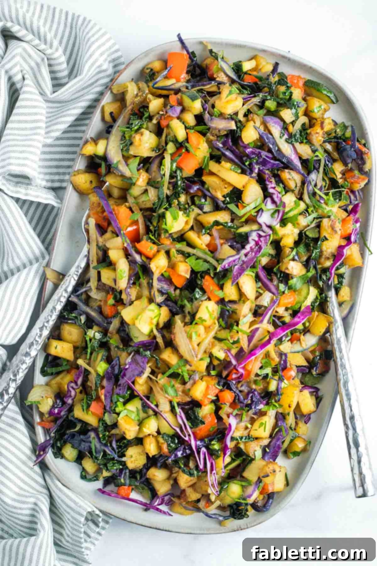Simple Skillet Vegan Potato & Vegetable Hash 2 Vibrant and colorful vegetable and potato hash featuring red cabbage, red peppers, fresh kale, and zucchini, ready to be served from a skillet.