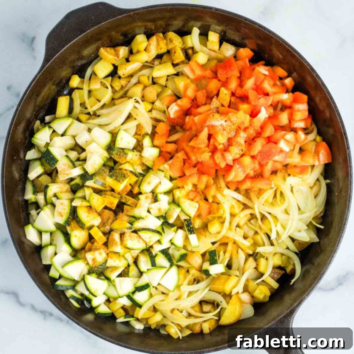 Simple Skillet Vegan Potato & Vegetable Hash 12 Diced zucchini and red bell pepper sprinkled with spices, added to the potato and onion mixture in a skillet.