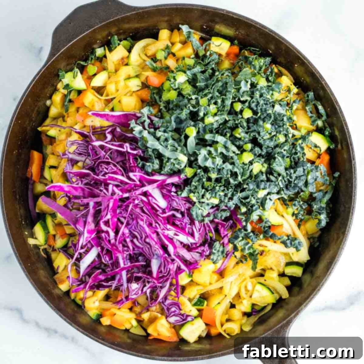 Simple Skillet Vegan Potato & Vegetable Hash 14 Thinly sliced kale and cabbage being added to the cooked potato and vegetable hash in a skillet, ready to wilt.