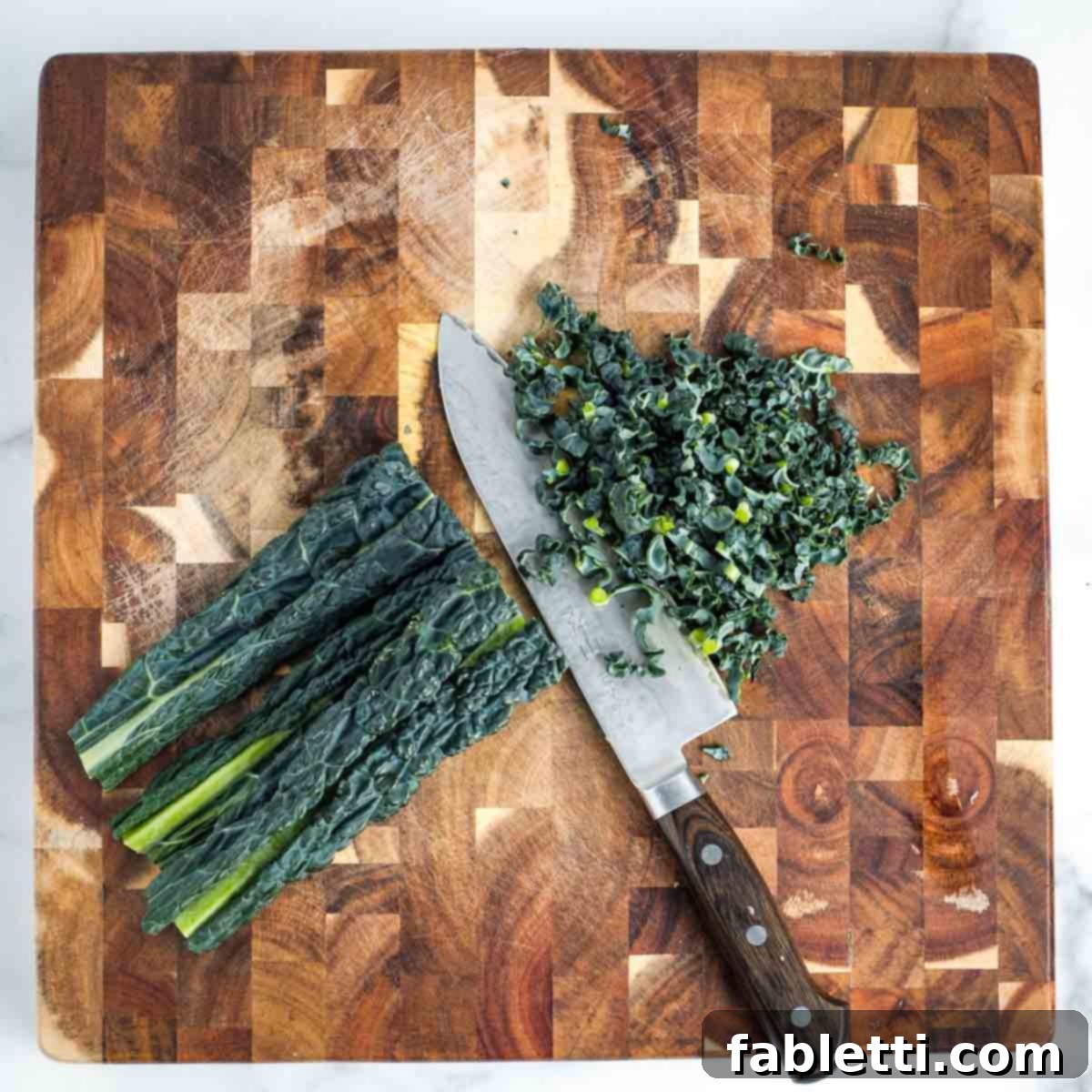 Simple Skillet Vegan Potato & Vegetable Hash 5 Stack of fresh Lacinato kale leaves being thinly sliced on a wooden board for the veggie hash.