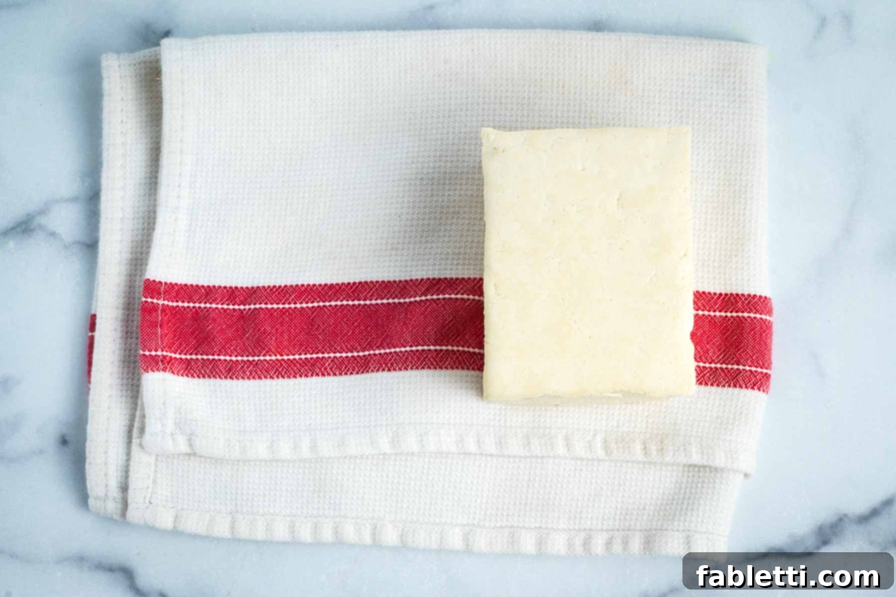 Dish towel with red stripe and a block of tofu.