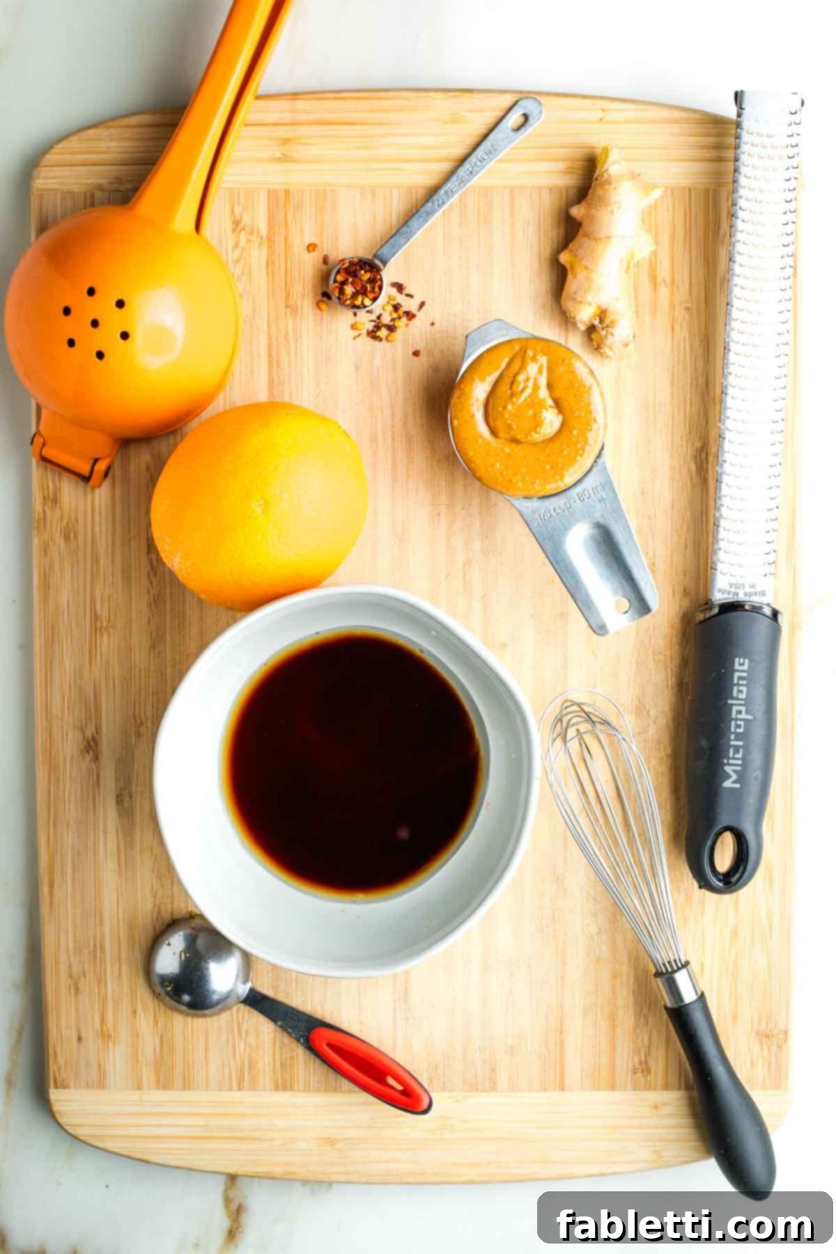 Fresh Spring Roll Salad Bowl with Creamy Peanut Sauce 5 Bowl with dark liquid, plus a messy wooden board with peanut butter, zester, orange and juice squeezer.