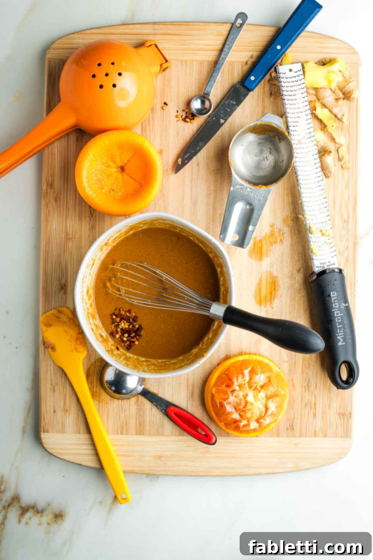 Fresh Spring Roll Salad Bowl with Creamy Peanut Sauce 7 Whisking peanut sauce with crushed red pepper on a wooden board with kitchen tools.