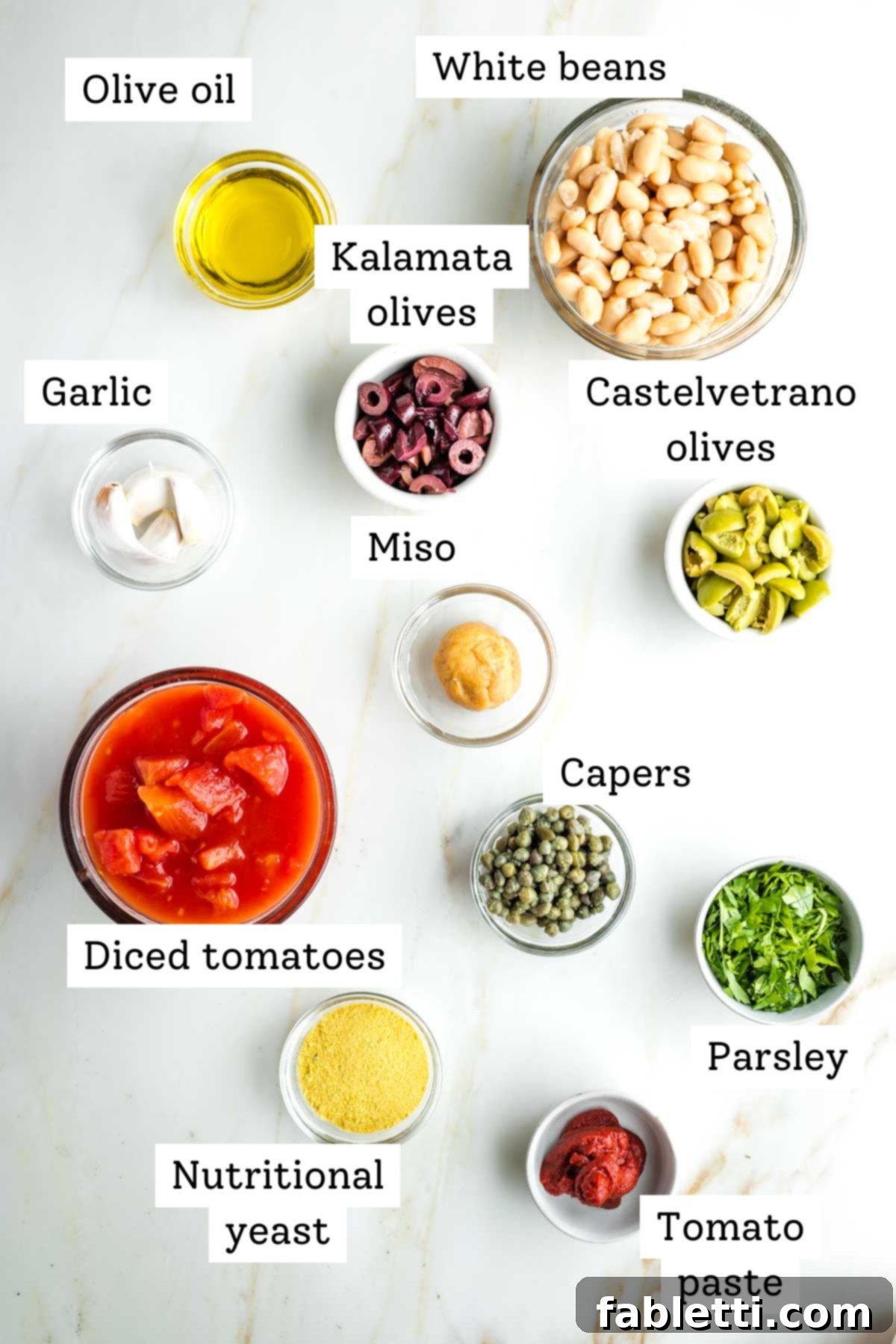 Zesty White Bean Puttanesca Pasta 3 Labeled ingredients for vegan pasta puttanesca, including olives, capers, miso paste, and diced tomatoes.