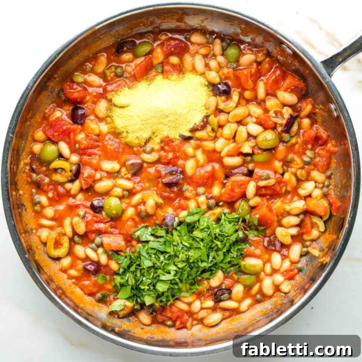 Zesty White Bean Puttanesca Pasta 9 Nutritional yeast and fresh chopped parsley sprinkled over a chunky puttanesca sauce with white beans.