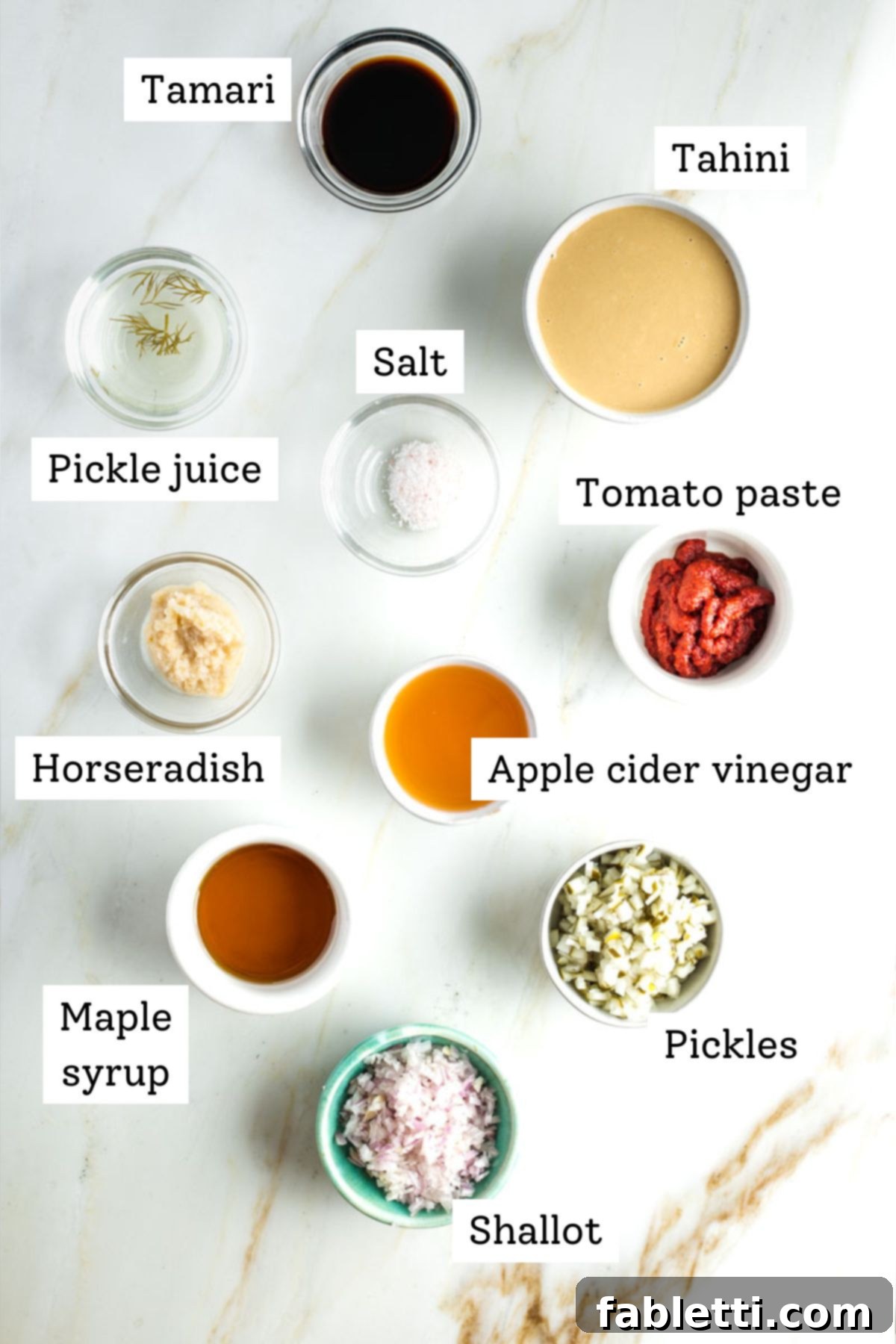 A selection of fresh ingredients including tahini, horseradish, pickles, and tomato paste, ready for making dressing.