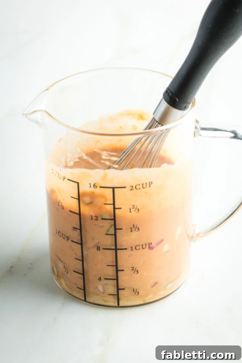 Whisking together chunky ingredients to make Russian dressing. 