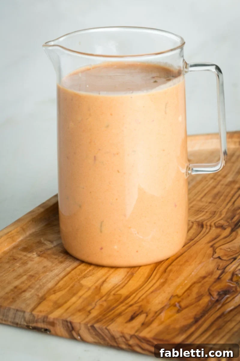 Small glass pitcher with creamy orange dressing. 