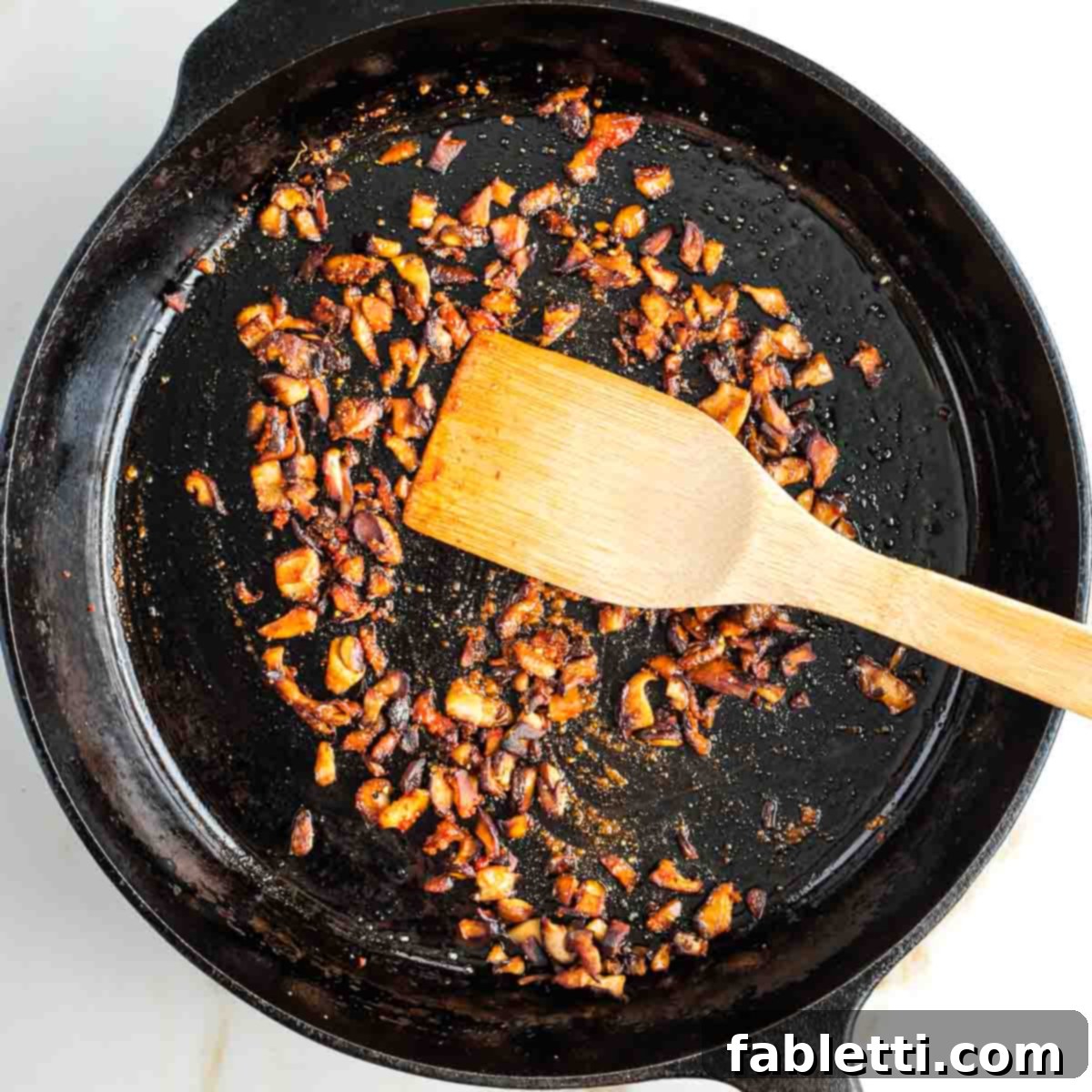 Smoky Shiitake and Zesty Russian Vegan Wedge 13 Wooden spatula pushing around diced and spiced shiitake mushrooms, now golden and crispy.