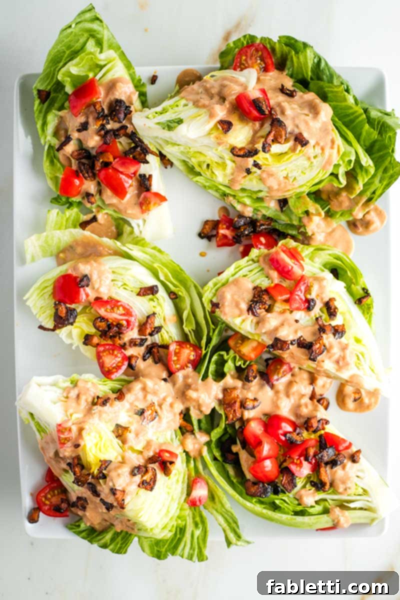 Smoky Shiitake and Zesty Russian Vegan Wedge 15 Wedges of iceberg lettuce on a platter, adorned with generous drizzles of Russian dressing, shiitake bacon crumbles, and chopped tomatoes.