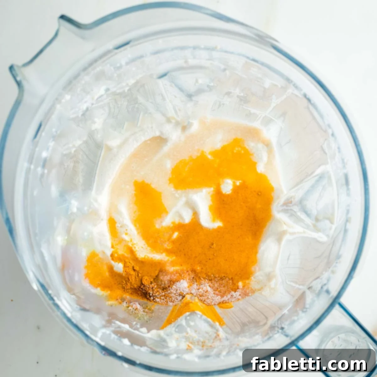 Caramelized Zucchini and Onion Creamy Dip 11 Cashew cream in a blender, gently sprinkled with vibrant turmeric, a pinch of salt, and a dash of fiery cayenne pepper, ready for blending.