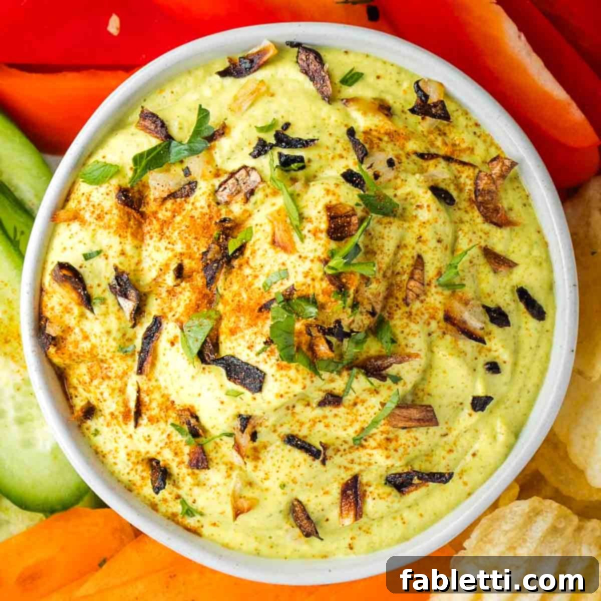 Caramelized Zucchini and Onion Creamy Dip 14 A bowl of thick and creamy, light green dip, beautifully garnished with finely chopped crispy onions, fresh parsley, and a dusting of paprika, showcasing its irresistible appeal.