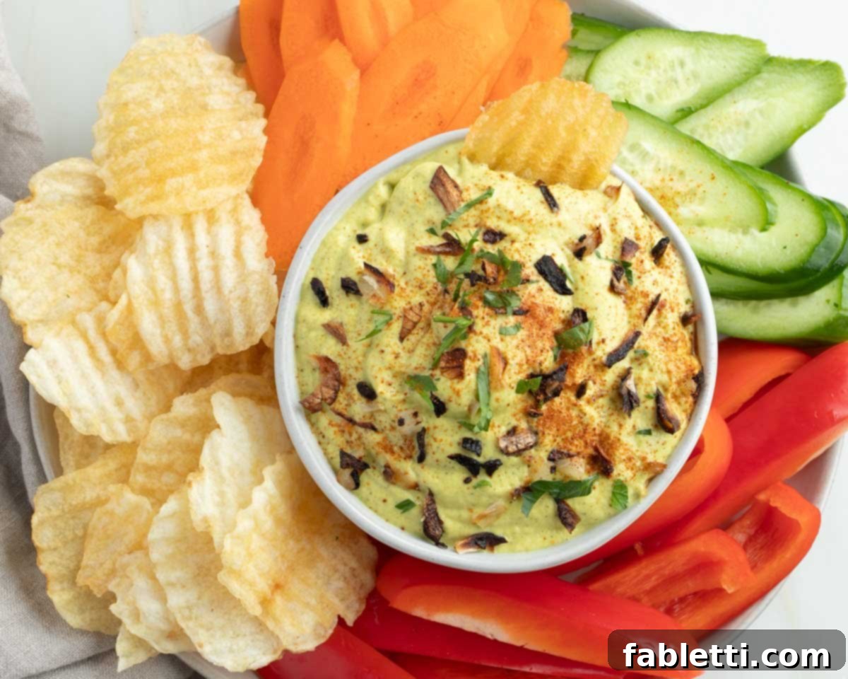 Caramelized Zucchini and Onion Creamy Dip 15 A beautiful spread featuring the vegan French onion dip surrounded by a colorful assortment of fresh vegetables and crispy potato chips, illustrating perfect serving suggestions.
