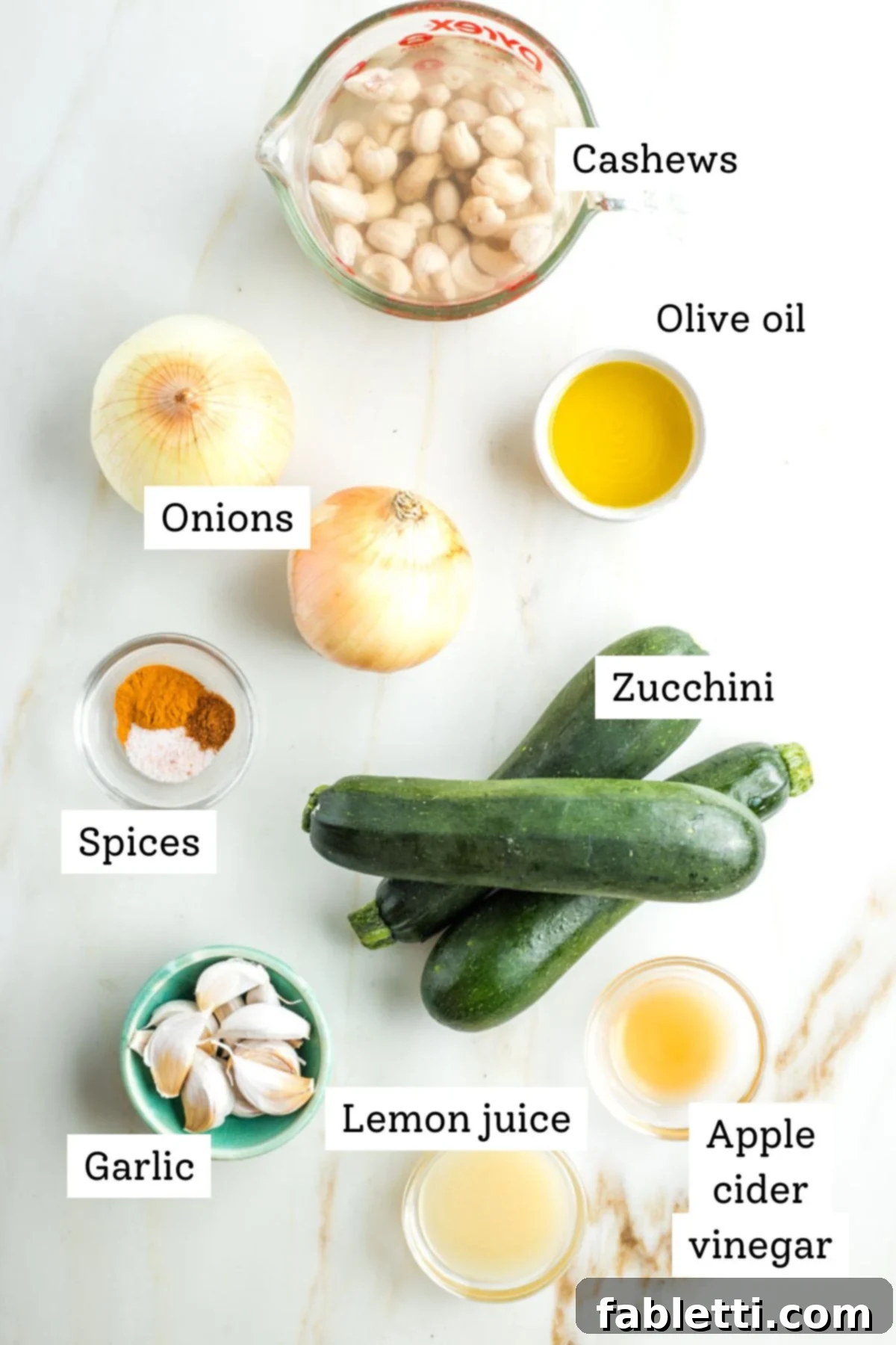 Caramelized Zucchini and Onion Creamy Dip 3 A curated selection of labeled ingredients including cashews, zucchini, onion, garlic, lemon juice, apple cider vinegar, various spices, and olive oil, laid out neatly for the vegan dip recipe.