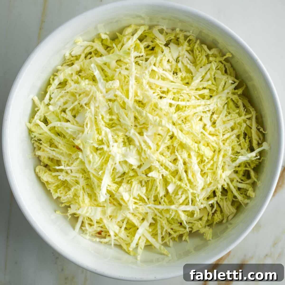 Shredded savoy cabbage in a white bowl.