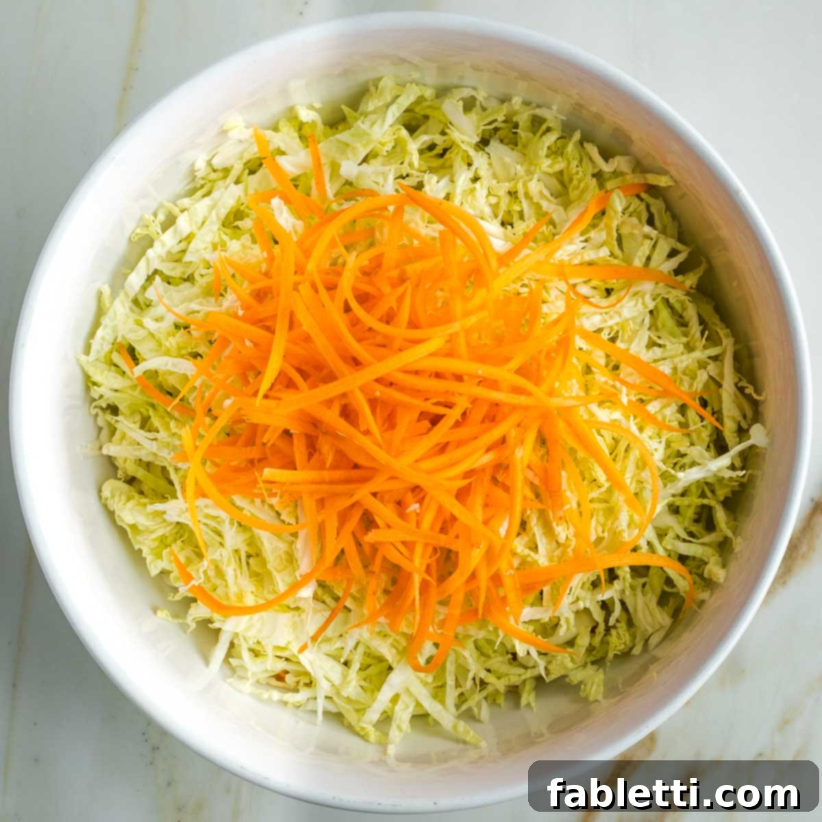 Shredded cabbage and carrot in a bowl.