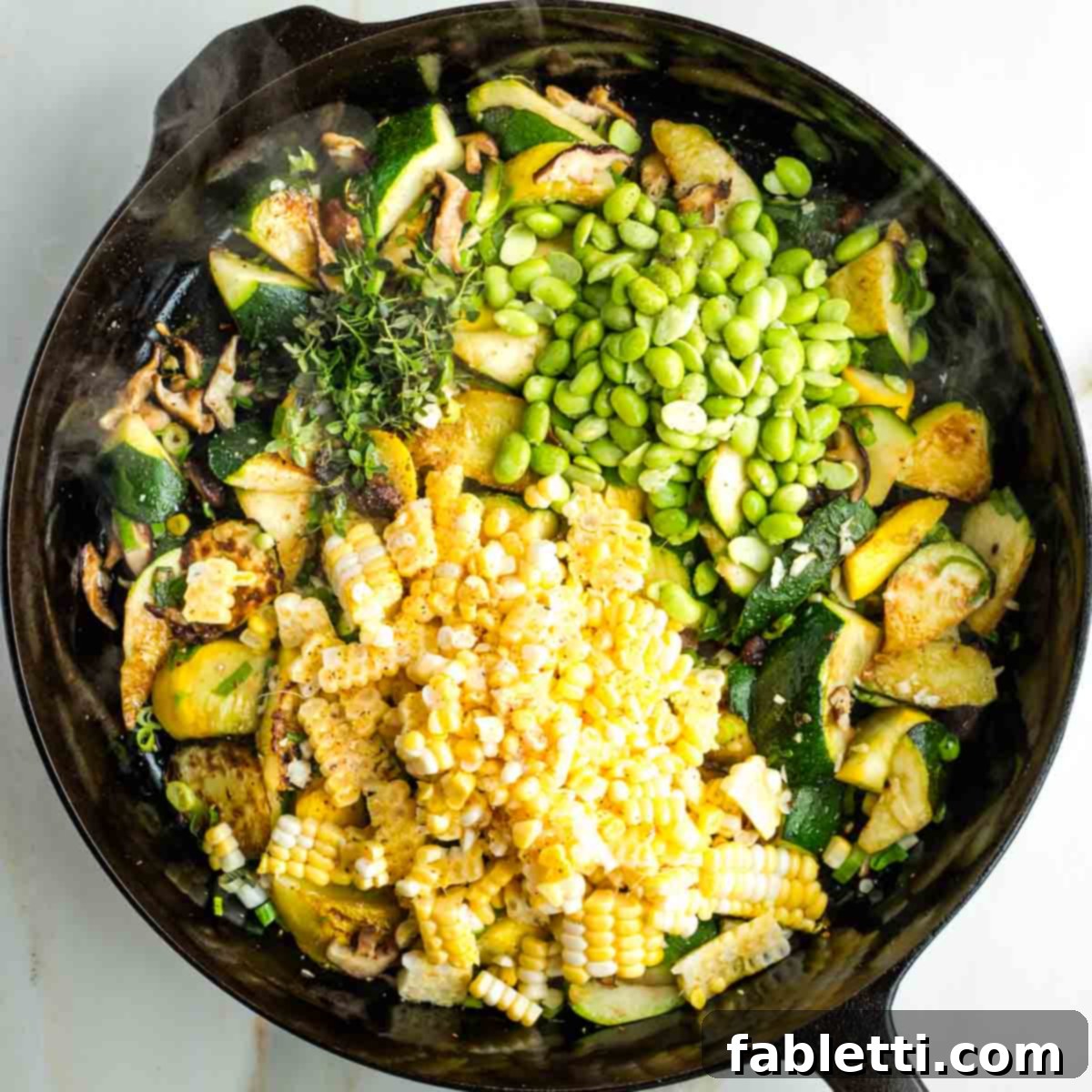 Vegan Zucchini Skillet Dinner in Just 20 Minutes 11 Corn kernels, edamame beans and fresh thyme on top of charred zucchini and mushrooms in a skillet.
