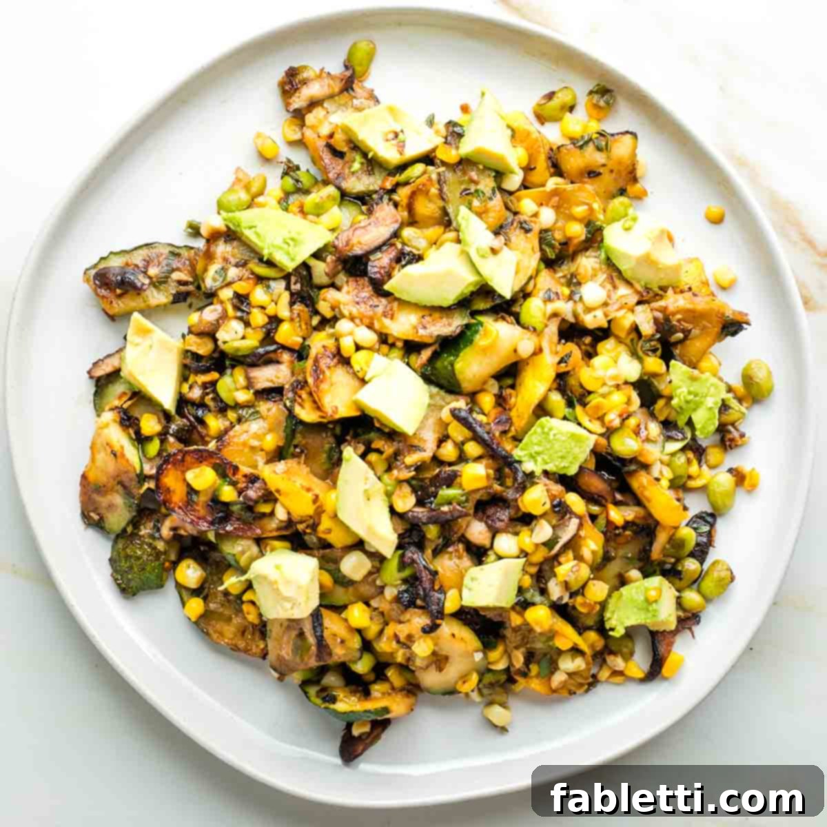 Vegan Zucchini Skillet Dinner in Just 20 Minutes 15 Close up of a hand stirring the vibrant zucchini skillet dinner in a cast iron pan.