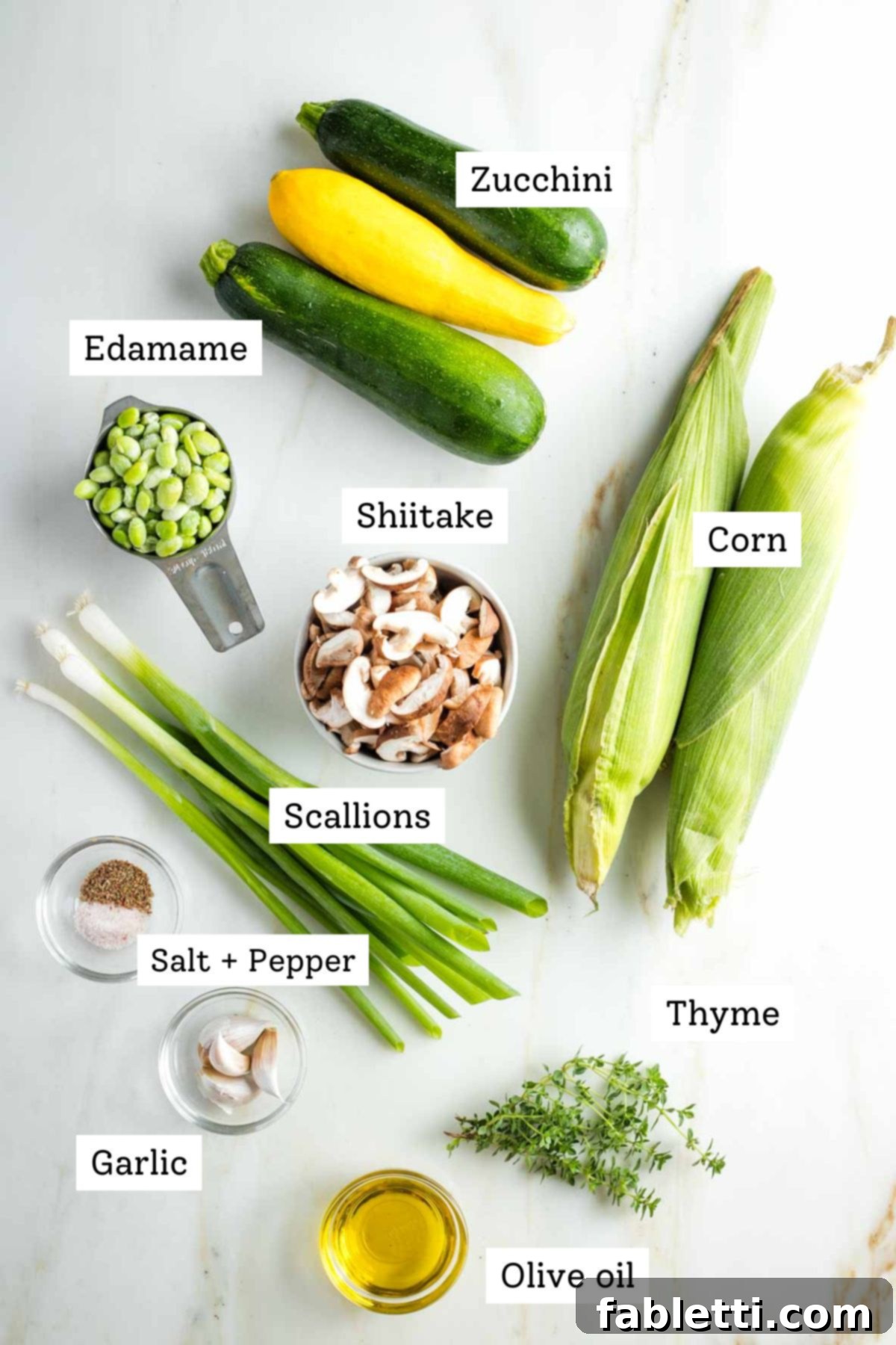 Vegan Zucchini Skillet Dinner in Just 20 Minutes 3 Labeled ingredients: zucchini, edamame, shiitake mushrooms, corn on the cob, salt and pepper, fresh thyme, scallions, olive oil, garlic cloves, highlighting the fresh produce.