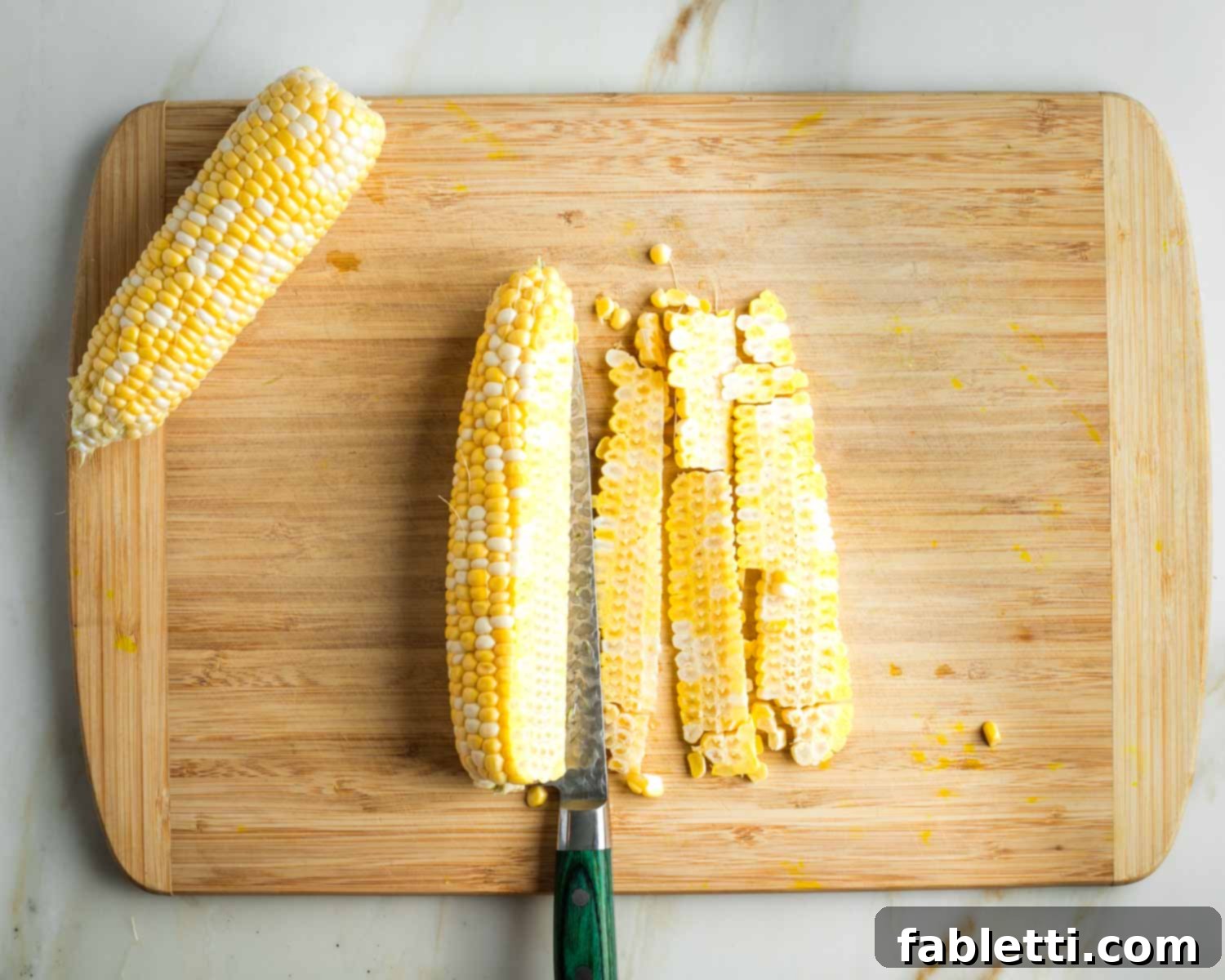 Vegan Zucchini Skillet Dinner in Just 20 Minutes 5 Slicing kernels off an ear of corn on the cob, laid flat on a wooden board.