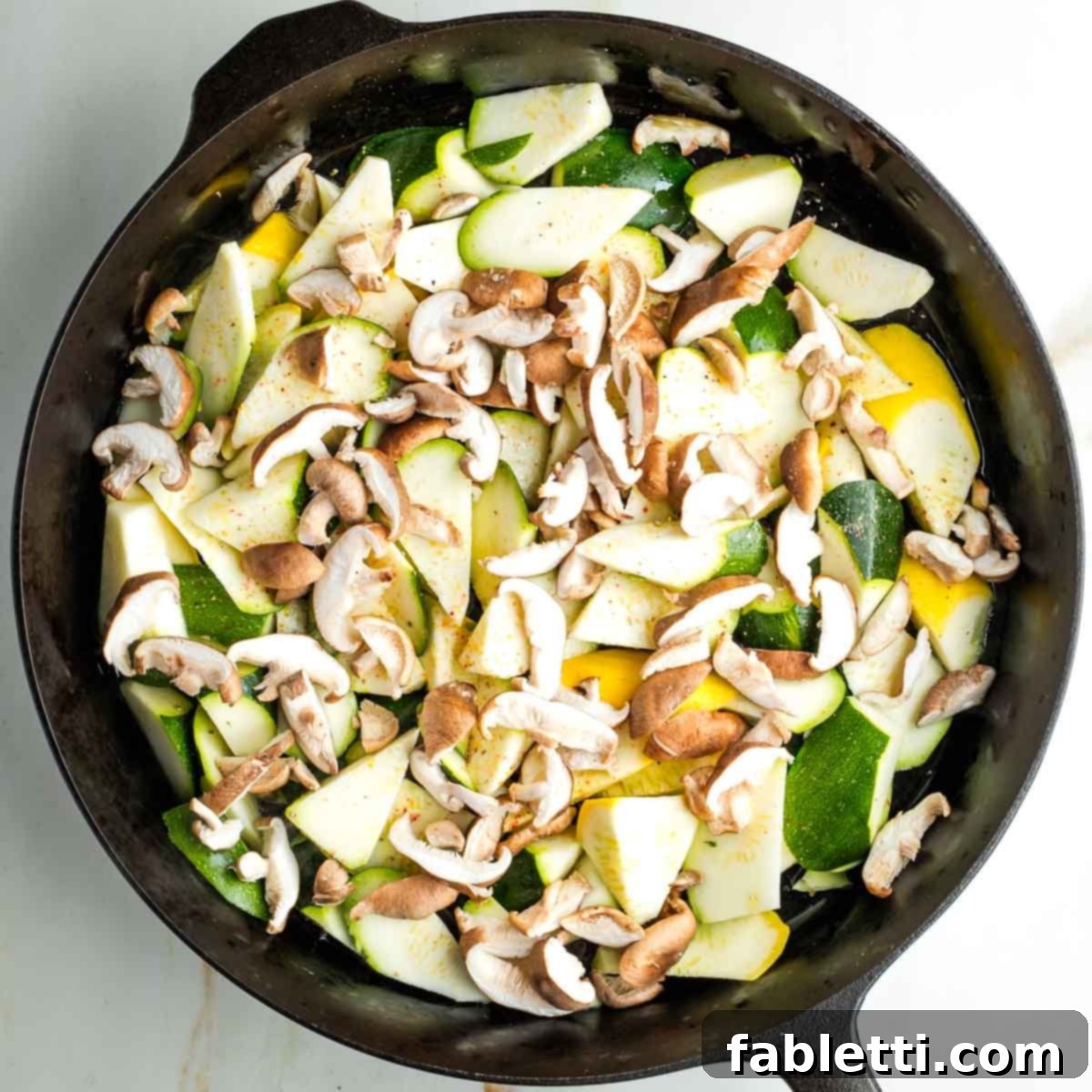Vegan Zucchini Skillet Dinner in Just 20 Minutes 8 Raw zucchini and yellow summer squash in a skillet with sliced shiitake mushrooms sprinkled with salt and pepper.