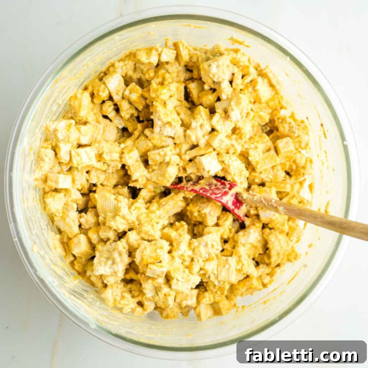 Zingy Vegan Tofu Egg Salad 14 Cubes and small torn pieces of tofu mixed with creamy yellow sauce.