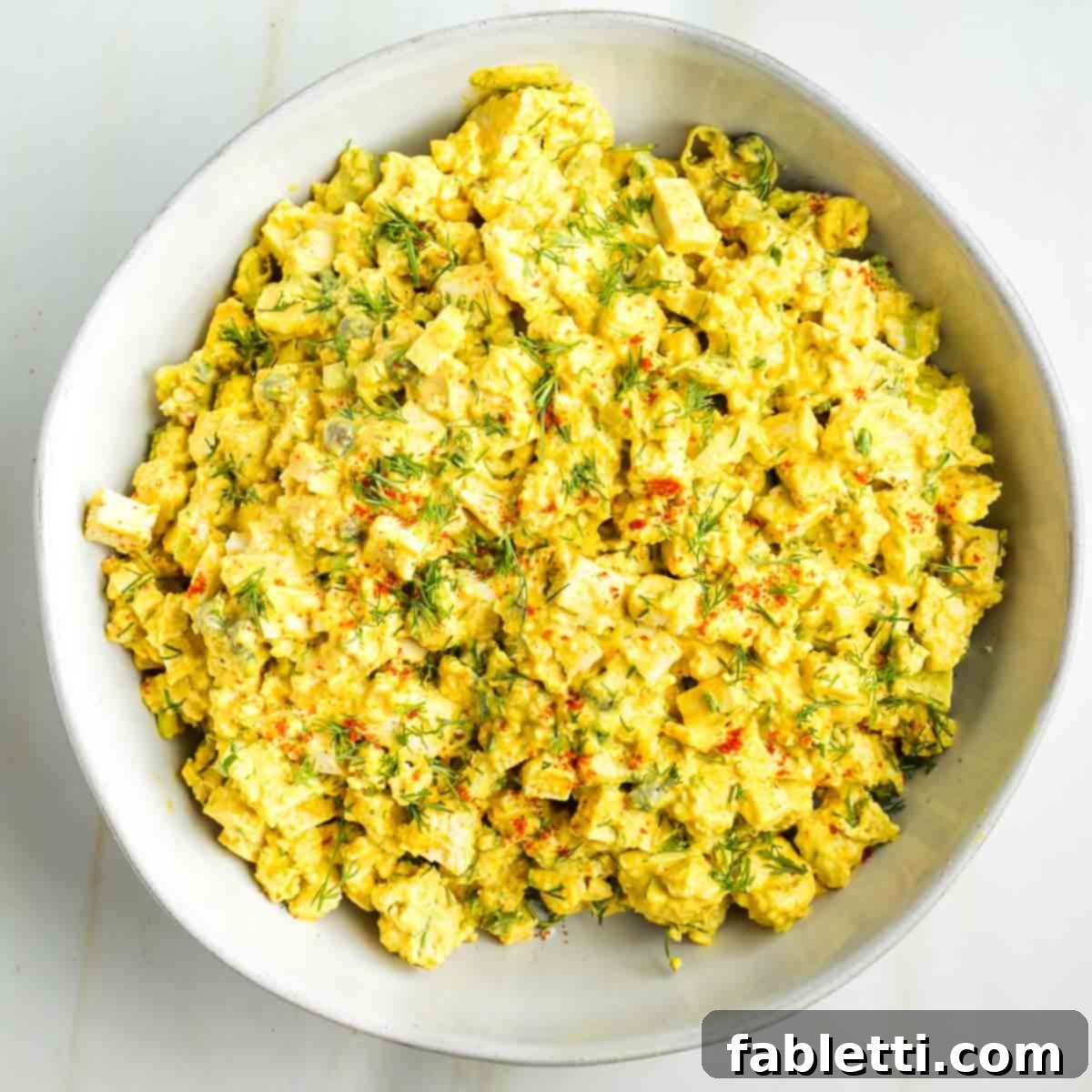 Zingy Vegan Tofu Egg Salad 16 Chunks of celery, scallions and fresh dill and what looks like egg salad, sprinkled with paprika.