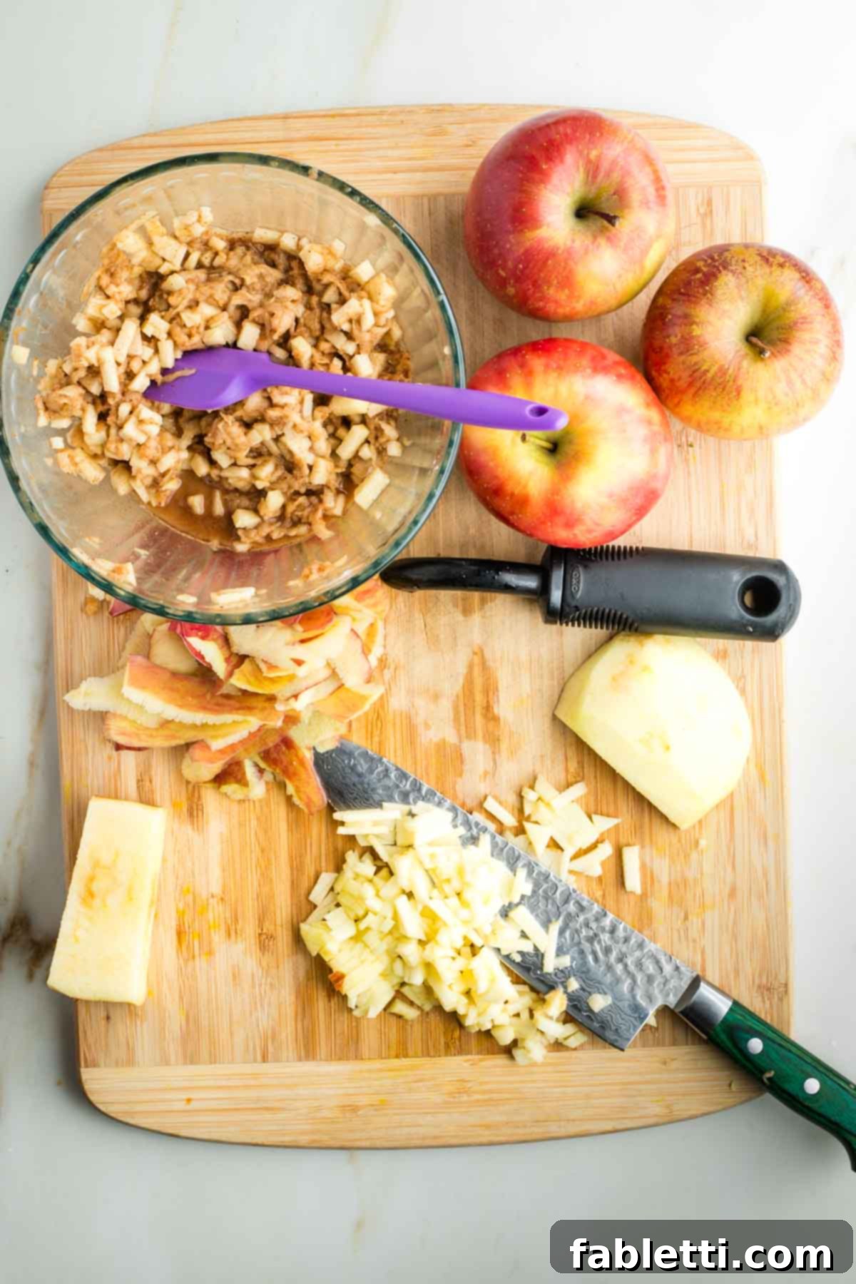 Apples being diced into small, uniform pieces and added to the bowl with the grated apple and spice mixture.